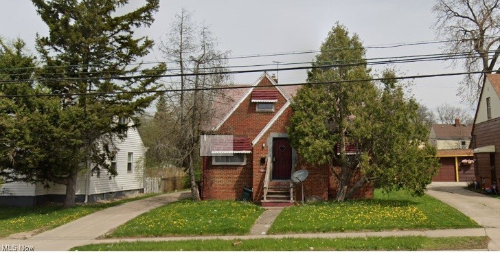 view of front of property featuring entry steps, a front lawn, and brick siding