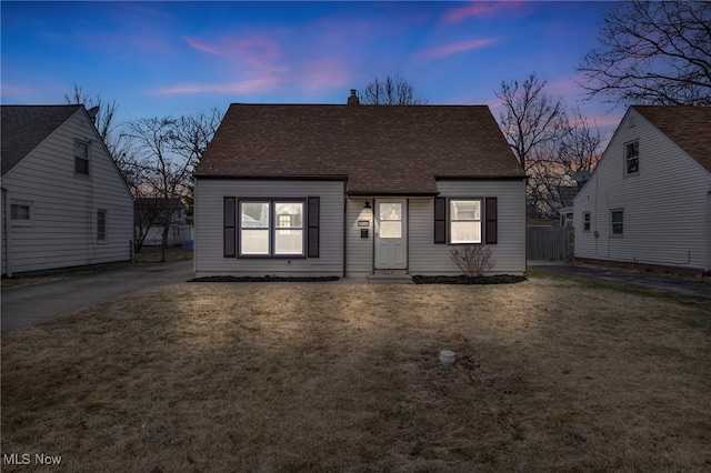 view of front of property with a chimney, a shingled roof, a front yard, and fence