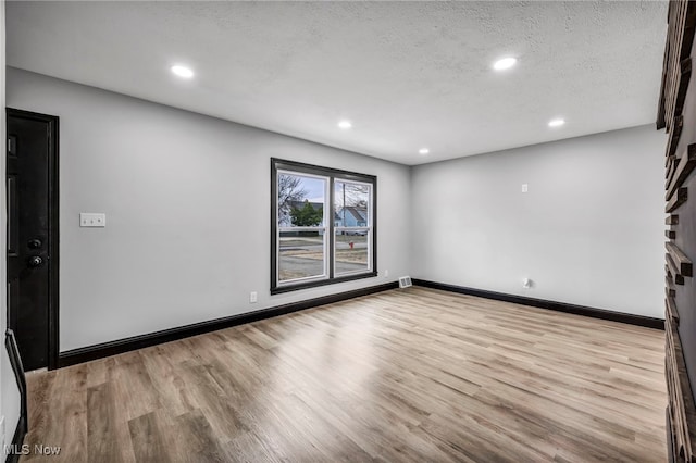 unfurnished room featuring recessed lighting, baseboards, a textured ceiling, and wood finished floors