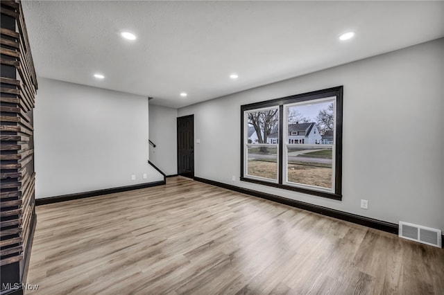 empty room with light wood-type flooring, visible vents, recessed lighting, baseboards, and stairs