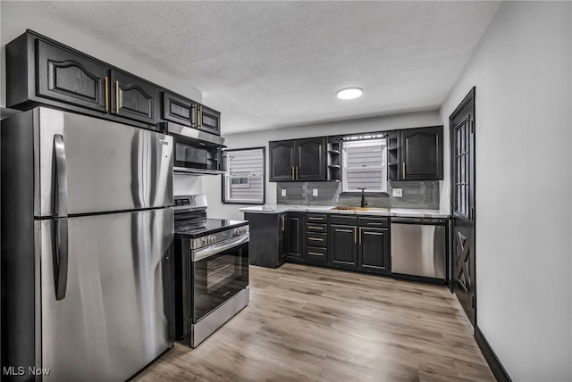 kitchen with light wood-style flooring, open shelves, a sink, appliances with stainless steel finishes, and light countertops