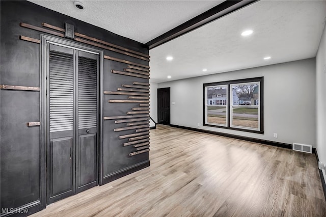 empty room featuring wood finished floors, baseboards, visible vents, recessed lighting, and a textured ceiling