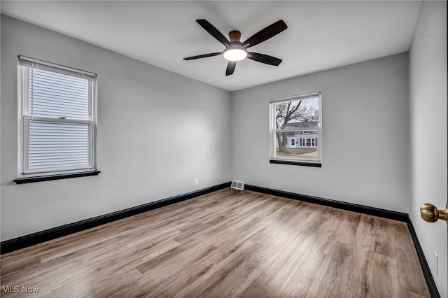 empty room featuring visible vents, baseboards, wood finished floors, and a ceiling fan