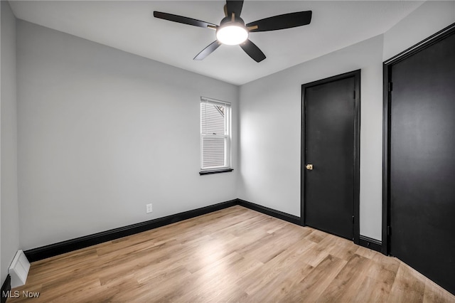 unfurnished bedroom with light wood-style flooring, a ceiling fan, and baseboards