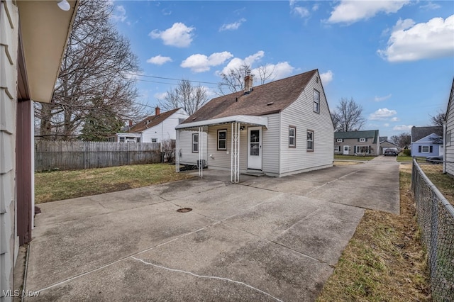 rear view of property featuring a patio area, a lawn, driveway, and fence