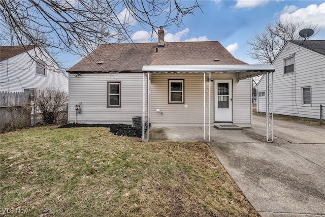 rear view of property with fence, roof with shingles, a yard, a chimney, and a patio area