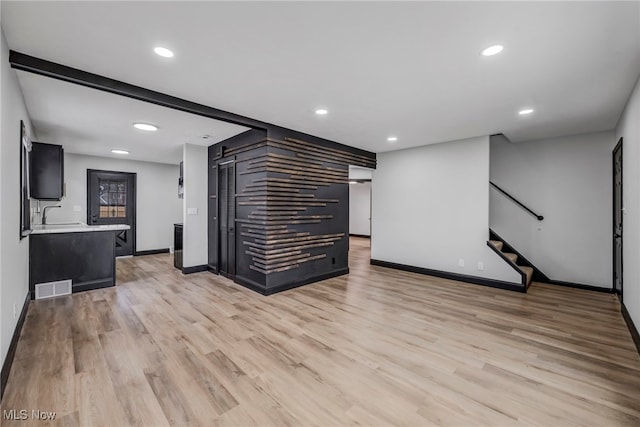 unfurnished living room featuring visible vents, baseboards, light wood-type flooring, stairs, and recessed lighting