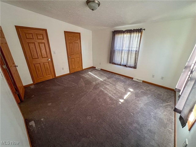 50055 Carroll Rd, East Liverpool, OH 43920 - unfurnished bedroom with visible vents, baseboards, a textured ceiling, and dark carpet
