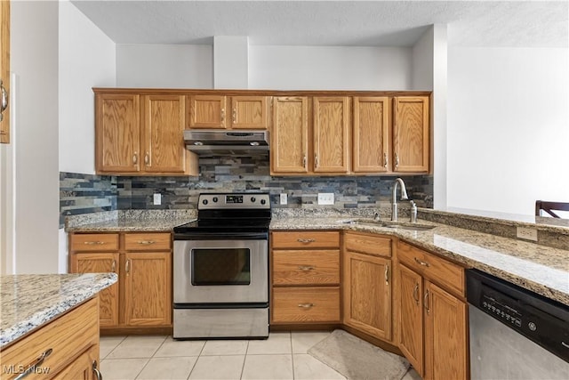 kitchen with tasteful backsplash, under cabinet range hood, light tile patterned floors, appliances with stainless steel finishes, and a sink