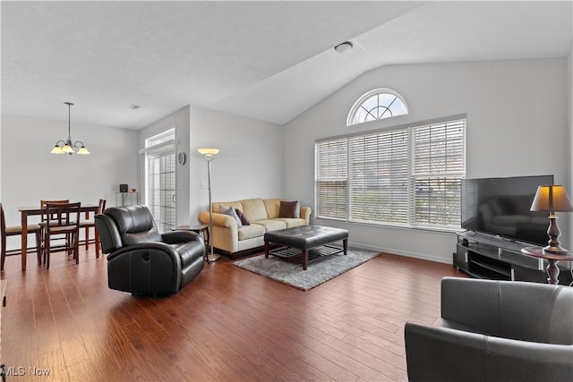 living room with baseboards, lofted ceiling, a notable chandelier, and wood finished floors
