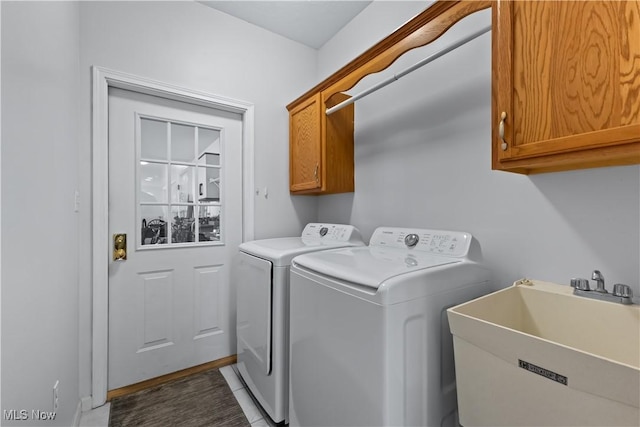 clothes washing area featuring separate washer and dryer, cabinet space, and a sink