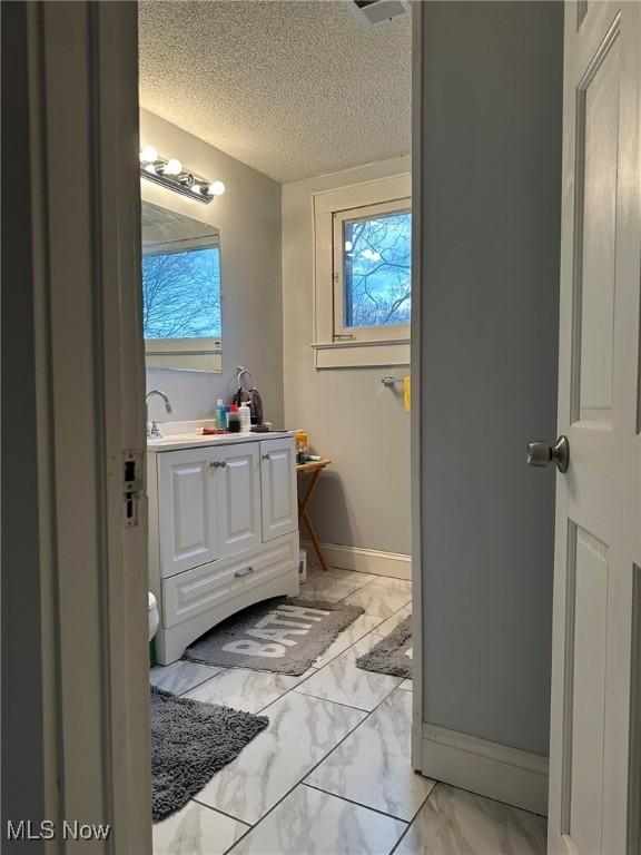 174 Colony Cres, Akron, OH 44305 - bathroom with marble look tiles, vanity, baseboards, and a textured ceiling