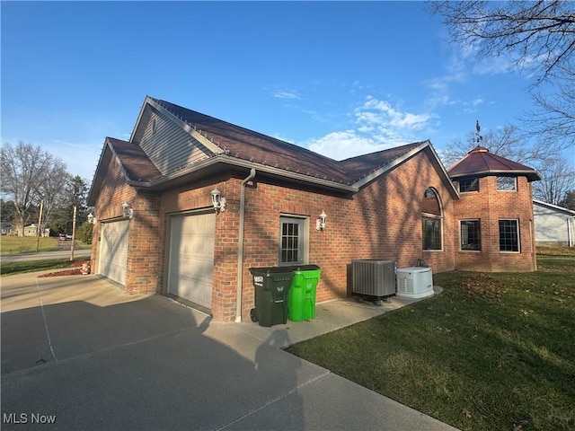 31 Briar Ln, Millersburg, OH 44654 - view of side of property featuring central AC unit, concrete driveway, brick siding, an attached garage, and a yard