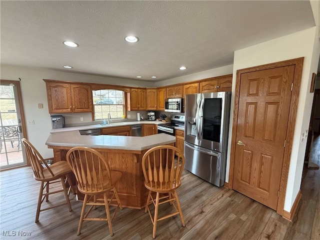 31 Briar Ln, Millersburg, OH 44654 - kitchen with a kitchen breakfast bar, brown cabinetry, light wood-type flooring, light countertops, and appliances with stainless steel finishes