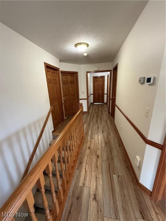 31 Briar Ln, Millersburg, OH 44654 - hall with hardwood / wood-style flooring, baseboards, an upstairs landing, and a textured ceiling
