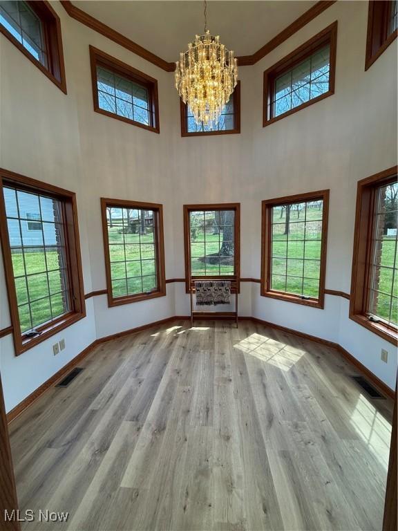 31 Briar Ln, Millersburg, OH 44654 - unfurnished living room with baseboards, visible vents, a chandelier, a high ceiling, and crown molding