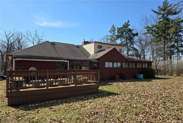 rear view of property with a shingled roof and a deck