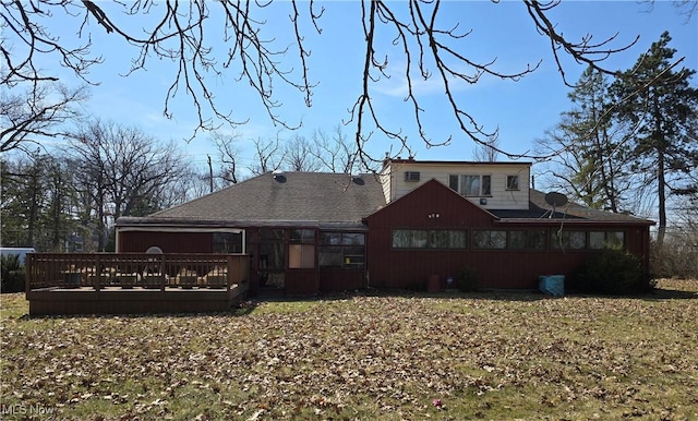 back of house with a wooden deck, roof with shingles, and a sunroom