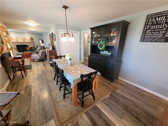 145 Maplewood Ave, Rittman, OH 44270 - dining space with baseboards, a notable chandelier, wood finished floors, and a fireplace