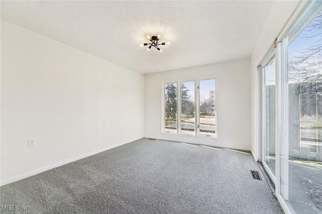 carpeted empty room featuring visible vents, baseboards, and a textured ceiling