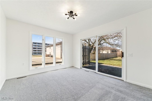 carpeted empty room with visible vents and baseboards