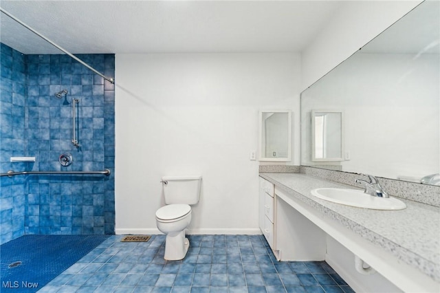 bathroom with tile patterned flooring, baseboards, toilet, a tile shower, and vanity