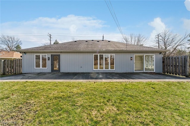 rear view of house with a patio, a lawn, and fence