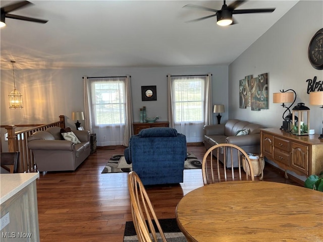 dining area with wood finished floors, ceiling fan with notable chandelier, baseboards, and vaulted ceiling