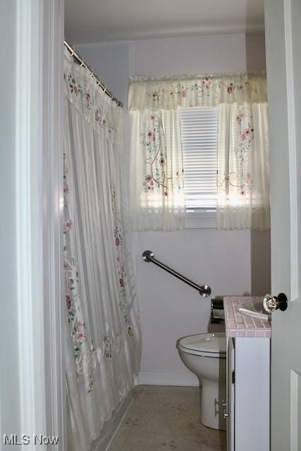full bathroom featuring curtained shower, baseboards, toilet, and vanity