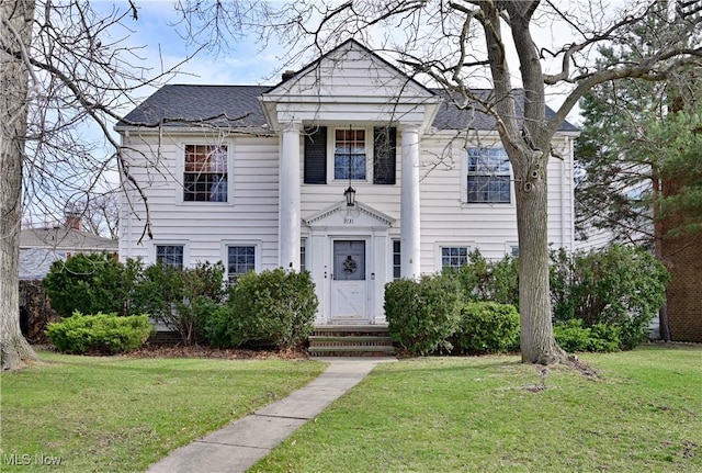 neoclassical / greek revival house featuring a shingled roof and a front lawn