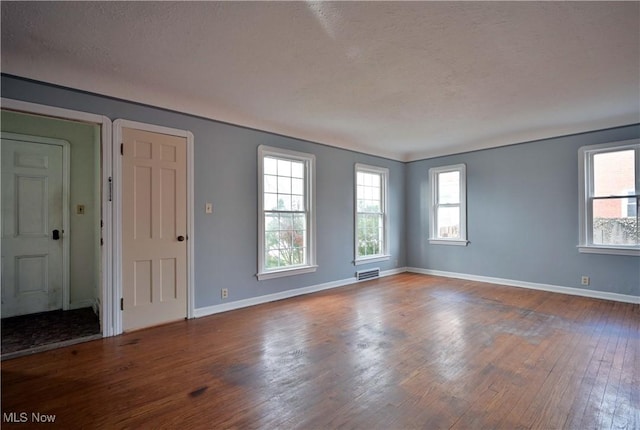empty room with visible vents, baseboards, and wood finished floors