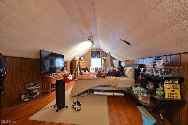 bedroom with wood walls, lofted ceiling, and wood-type flooring