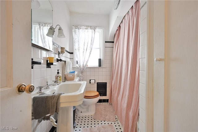 bathroom featuring heating unit, tile patterned flooring, curtained shower, tile walls, and toilet