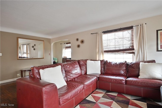 living area featuring baseboards and arched walkways