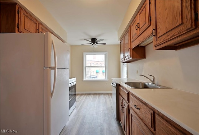 kitchen featuring brown cabinetry, stainless steel appliances, light countertops, and a sink
