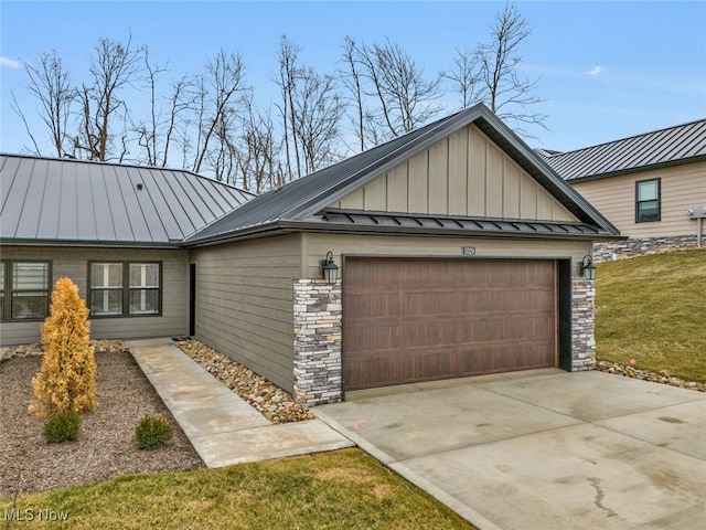exterior space featuring concrete driveway, metal roof, a garage, stone siding, and a standing seam roof