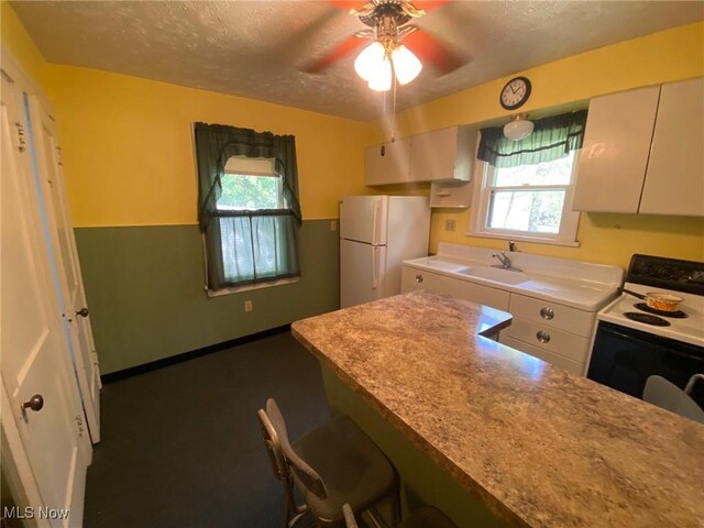 5208 Orchard Park Dr, Parma, OH 44134 - kitchen with range with electric stovetop, freestanding refrigerator, a textured ceiling, a ceiling fan, and a sink