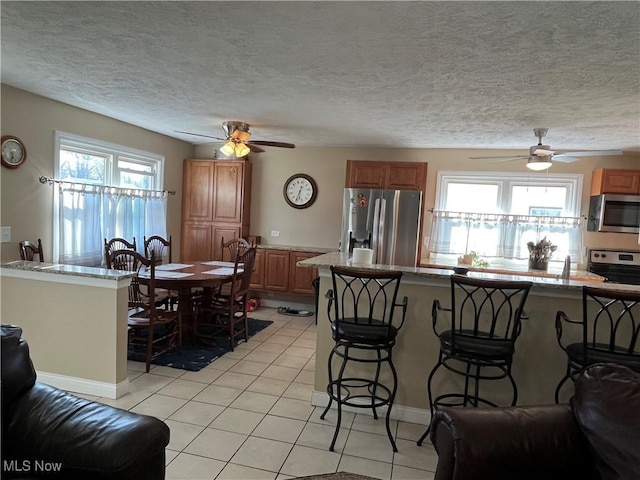 kitchen with a kitchen bar, a ceiling fan, and stainless steel appliances