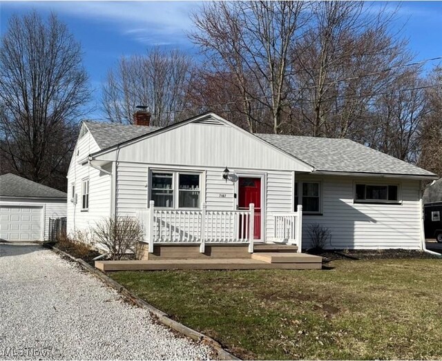 view of front of property with gravel driveway, an outdoor structure, a front yard, a garage, and a chimney