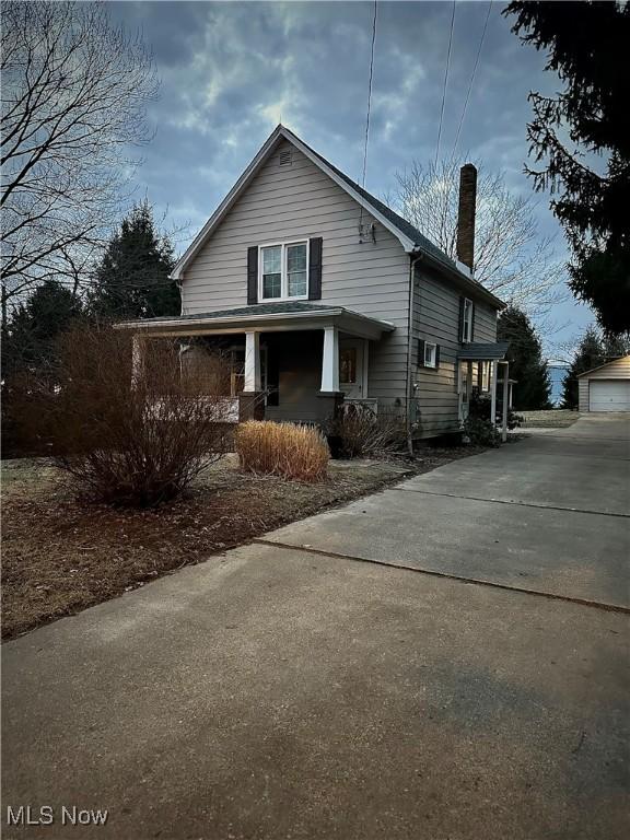 view of home's exterior featuring an outdoor structure, a garage, covered porch, and a chimney