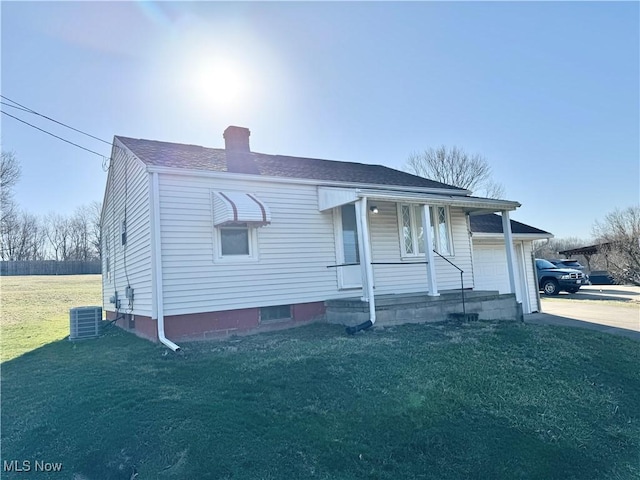 view of front of house featuring covered porch, a chimney, a front lawn, concrete driveway, and central air condition unit