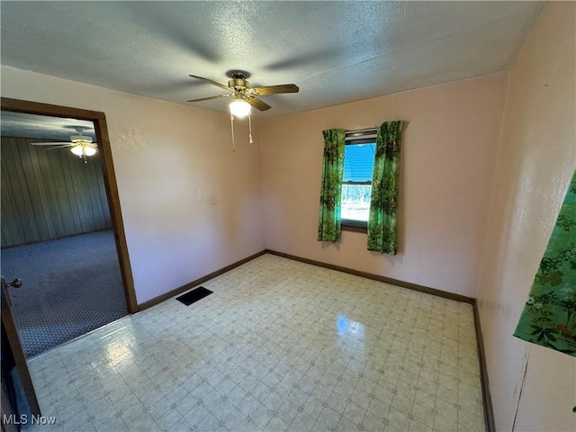 spare room featuring tile patterned floors, visible vents, a ceiling fan, a textured ceiling, and baseboards
