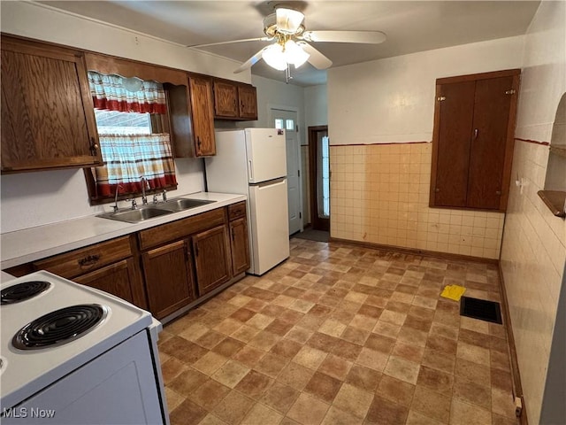 kitchen with visible vents, ceiling fan, white appliances, tile walls, and a sink