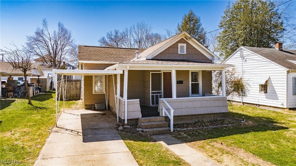 bungalow-style house featuring an attached carport, a front lawn, a porch, roof with shingles, and driveway
