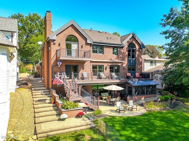 back of house with stairway, a yard, brick siding, a chimney, and a patio area