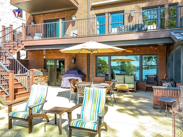 view of patio featuring a balcony, stairway, outdoor dining area, and grilling area
