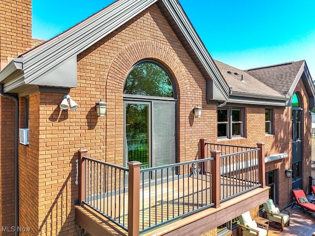 exterior space featuring brick siding, a balcony, and roof with shingles