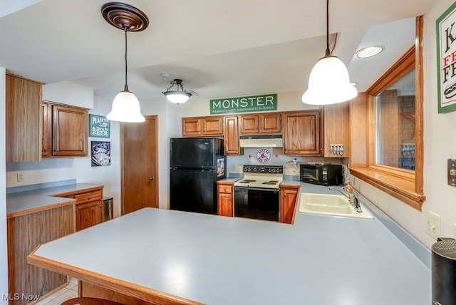 kitchen featuring under cabinet range hood, light countertops, a peninsula, black appliances, and a sink