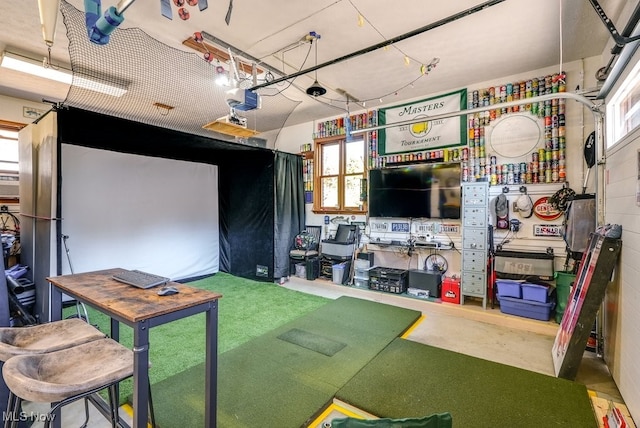 rec room featuring a garage, golf simulator, and concrete flooring