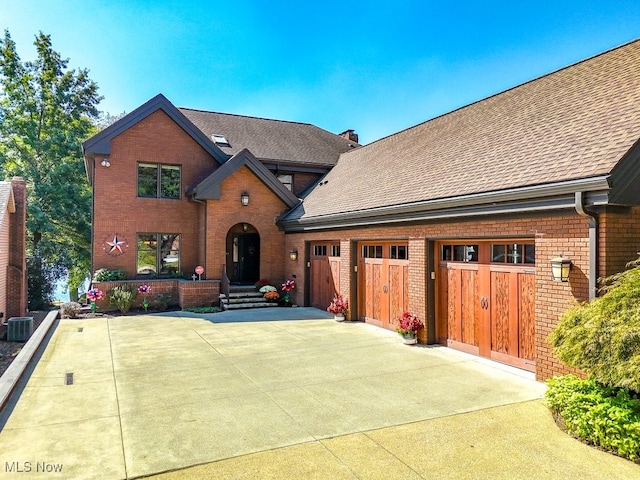 view of front facade featuring brick siding, concrete driveway, and roof with shingles